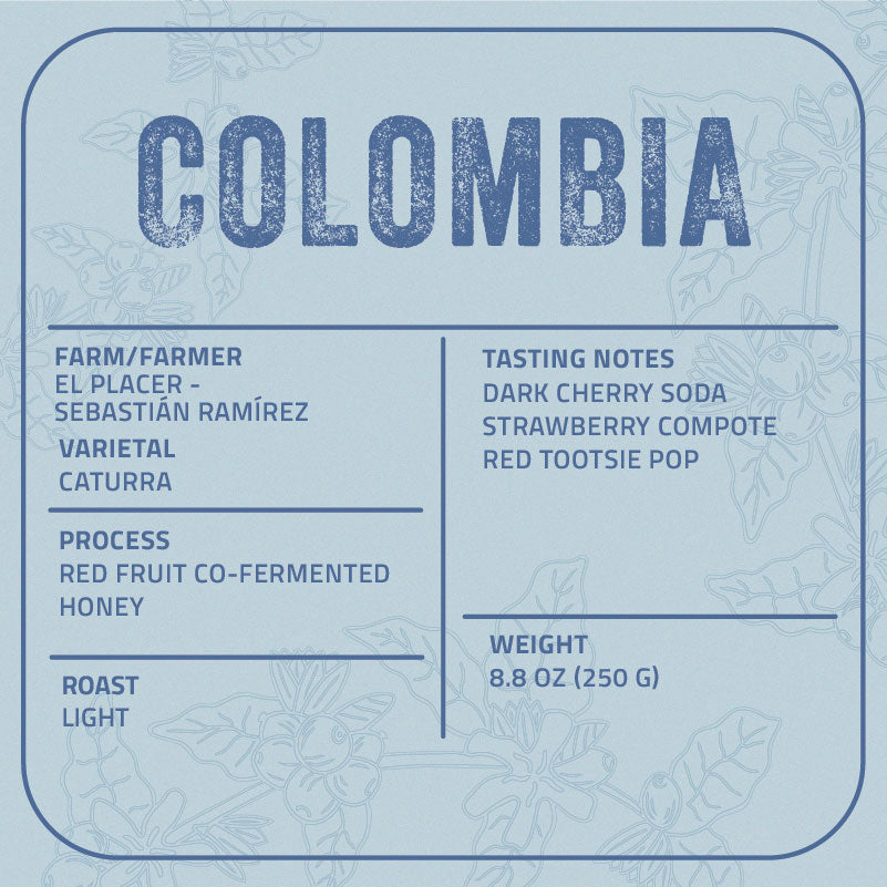 A light blue label card with rounded corners featuring the word 'COLOMBIA' at the top and product details for El Placer Honey in a typewriter-style font. The label includes tasting notes, processor, variety, and weight, with faint floral line art in the background.