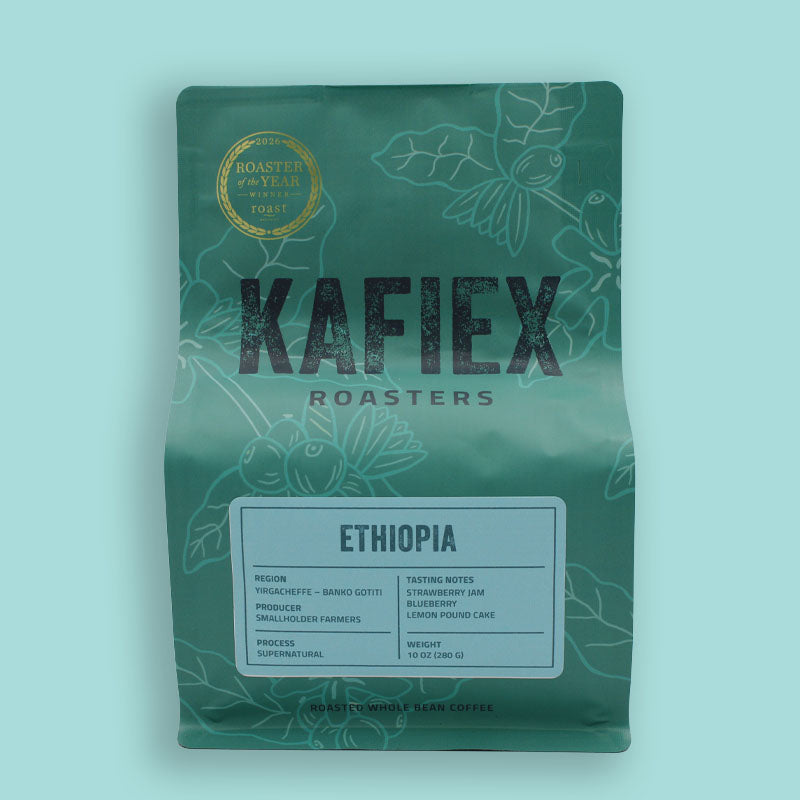 A stand-up pouch of KAFiEX ROASTERS Ethiopia coffee on a light aqua background. The pouch is dark green with white botanical line art, featuring a gold 'Roasted by Year 2023' seal and a white label with black text.
